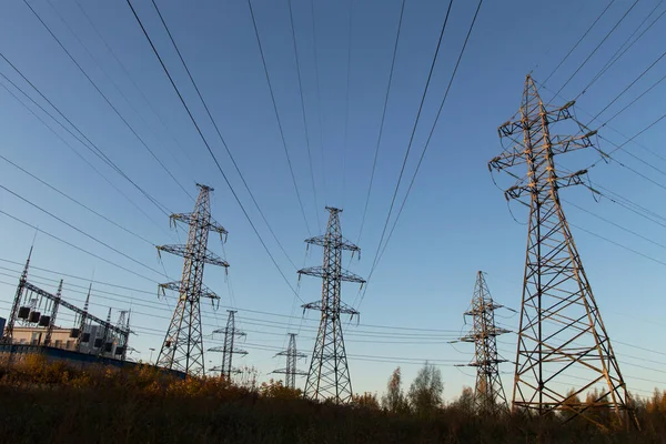Electric powerlines on electric substation and distribution power. High voltage power lines, pylons against blue sky