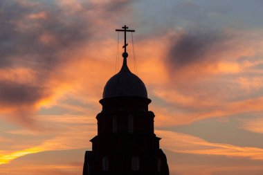 Gün batımında haçı olan kilise kubbesinin siyah silueti, gün doğumunda gökyüzü.