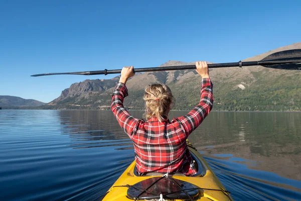 Beautiful Woman paddling a sea kayak while on vacation through the lakes and mountains of the national park.