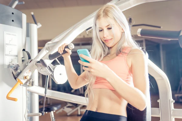 Женщина делает тренировки в тренажерном зале и проверяет свое расписание на й — стоковое фото