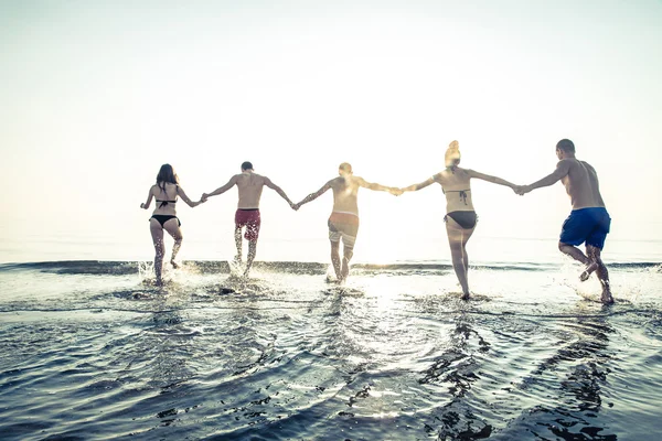 Friends running into water — Stock Photo, Image