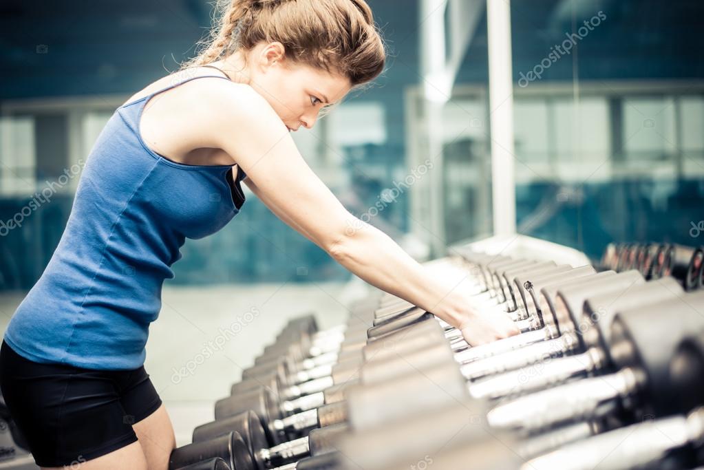 Woman taking dumbbells in a fitness gym