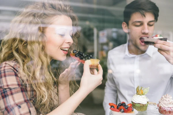 Pareja joven comiendo pasteles — Foto de Stock