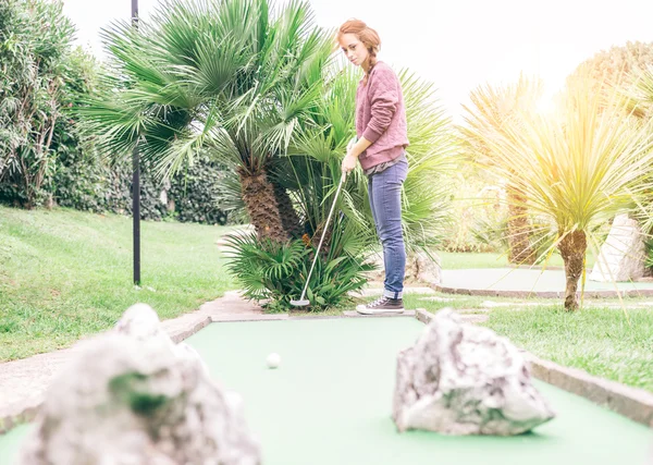 Женщина играет в мини-гольф — стоковое фото