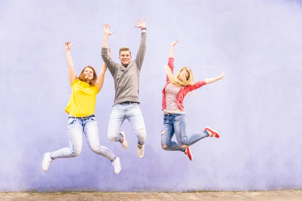 Amigos pulando em uma parede azul — Fotografia de Stock