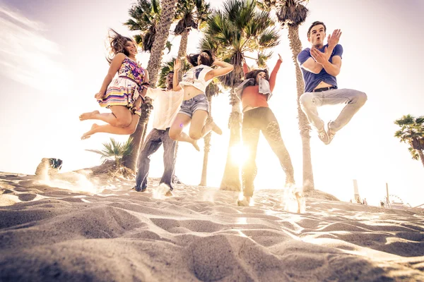 Друзья прыгают по пляжу — стоковое фото