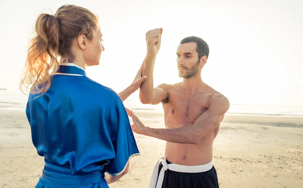 Coppia di studenti che allenano arti marziali sulla spiaggia — Foto Stock