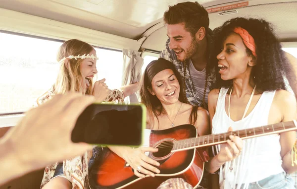 Друзья-хиппи веселятся в винтажном фургоне, играют на гитаре — стоковое фото