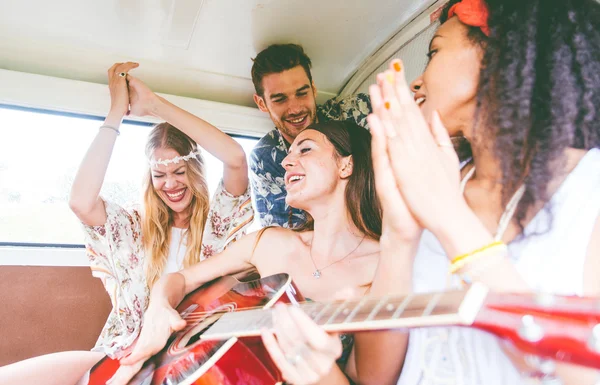 Hippie friends having fun into a vintage van, playing the guitar — Stock Photo, Image