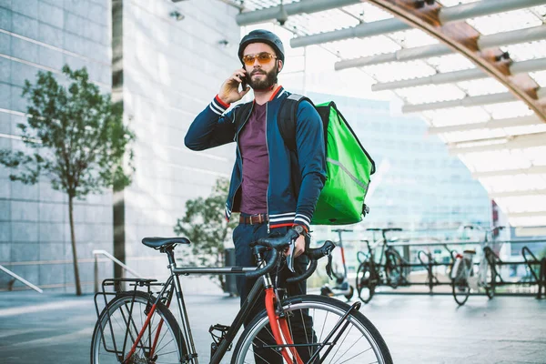 Food delivery rider on his bicycle. Image of a middle age man at work in the city center. Delivering pizza and burgers at home with the thermal backpack