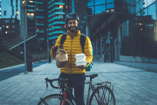 Food delivery rider on his bicycle. Image of a middle age man at work in the city center. Delivering pizza and burgers at home with the thermal backpack