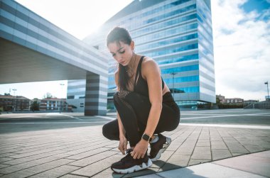 Şehir merkezinde kadın şehir koşucu eğitimi var. Güzel bir kadın sabahın köründe spor yapıyor.
