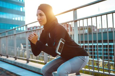 Şehir merkezinde Müslüman şehir koşucu eğitimi. Güzel bir kadın sabahın köründe spor yapıyor.