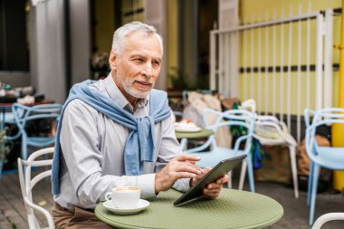 Neşeli son sınıf erkek portresi. Yetişkin yetişkin bilgisayarını bir barda kullanıyor. Yaşam tarzı, yaşlılar, teknoloji ve akıllı çalışma konseptleri.