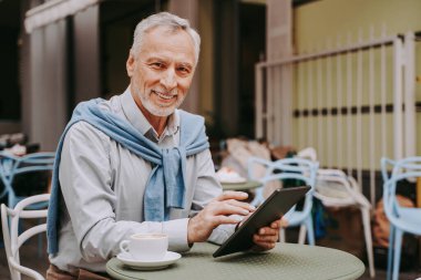 Neşeli son sınıf erkek portresi. Yetişkin yetişkin bilgisayarını bir barda kullanıyor. Yaşam tarzı, yaşlılar, teknoloji ve akıllı çalışma konseptleri.
