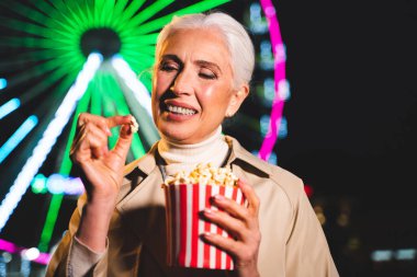 Pretty senior woman having fun at amusement park, concepts about elderly and lifestyle clipart