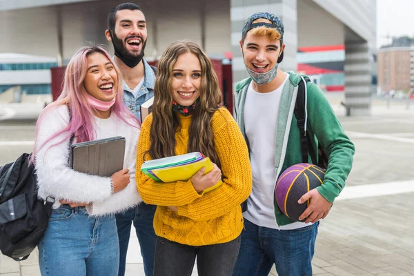 Happy young people meeting outdoors and wearing face masks during covid-19 pandemic - Group of cheerful teenagers having fun, concepts about teenage, lifestyle and generation z