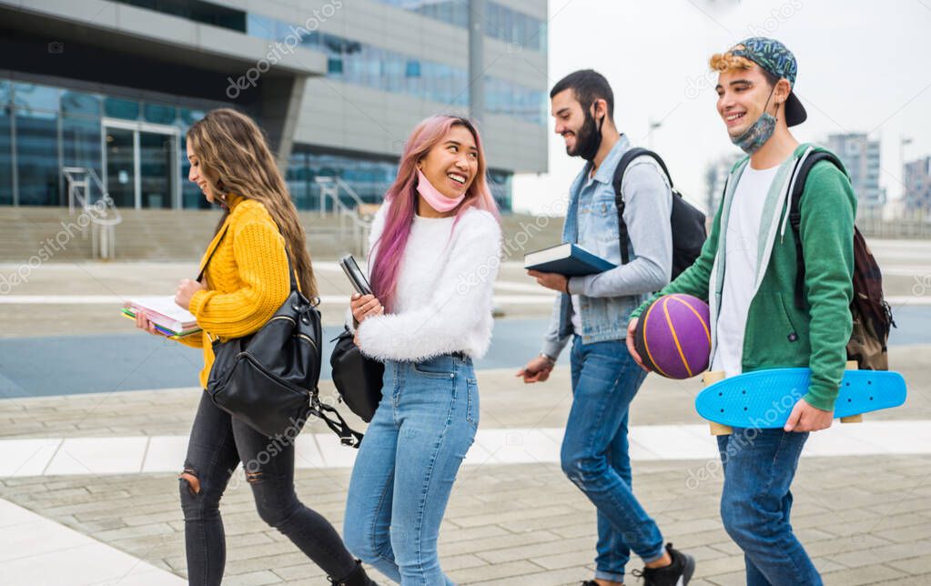 Happy young people meeting outdoors and wearing face masks during covid-19 pandemic - Group of cheerful teenagers having fun, concepts about teenage, lifestyle and generation z