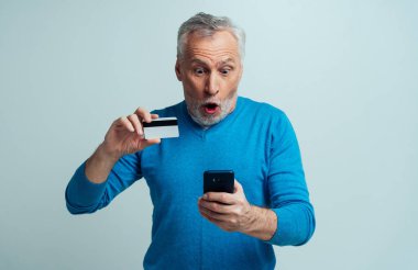 Yakışıklı son sınıf öğrencisi gri arka planda izole edilmiş. Yaşlı adam online alışveriş yapıyor. Üçüncü yaş ve kıdem kavramları