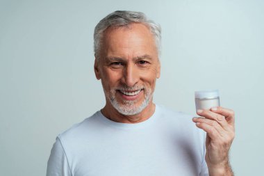 Yakışıklı son sınıf öğrencisi gri arka planda izole edilmiş. Üçüncü yaş ve kıdem kavramları