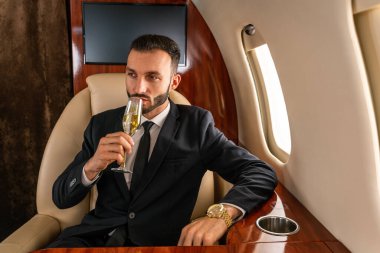 Zarif takım elbiseli yakışıklı bir işadamı özel jetle uçuyor başarılı bir girişimci özel iş sınıfında uçakta oturuyor iş ve traktörlük konseptleri
