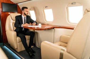 Zarif takım elbiseli yakışıklı bir işadamı özel jetle uçuyor başarılı bir girişimci özel iş sınıfında uçakta oturuyor iş ve traktörlük konseptleri