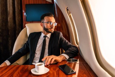 Zarif takım elbiseli yakışıklı bir işadamı özel jetle uçuyor başarılı bir girişimci özel iş sınıfında uçakta oturuyor iş ve traktörlük konseptleri