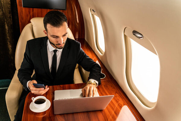 Красивый бизнесмен в элегантном костюме, летящий на эксклюзивном частном самолете - успешный предприниматель, сидящий в эксклюзивном бизнес-классе на самолете, концепции о бизнесе и trasportation
