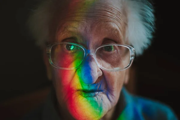 老太太一个人在房间里 95岁的祖母在想她的生活和回忆 从窗户投射到她脸上的彩虹光学照明弹 — 图库照片