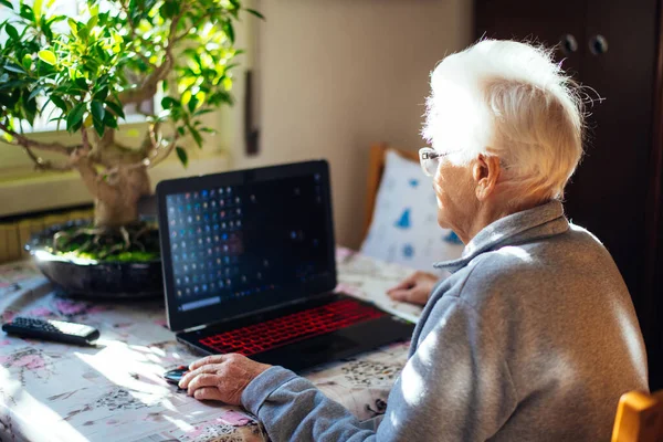 old woman alone in her room. 95 years old grandmother using laptop, and talking to the family online, through a video chat