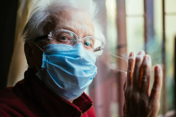 Old woman portrait at the window. Grandmother looking out on the street. \