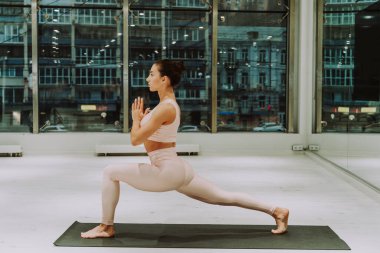 Güzel bir atletik kadın spor salonunda antrenman yapıyor, egzersiz yapmadan önce esneme egzersizleri yapıyor.