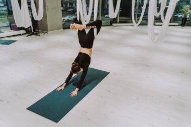 Güzel bir atletik kadın spor salonunda antrenman yapıyor, egzersiz yapmadan önce esneme egzersizleri yapıyor.