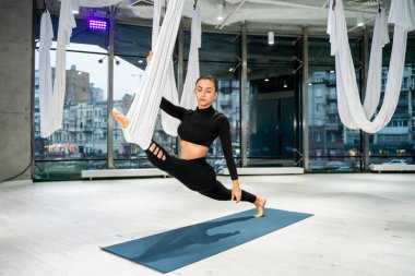 Güzel bir atletik kadın spor salonunda antrenman yapıyor, egzersiz yapmadan önce esneme egzersizleri yapıyor.
