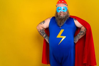 Süper kahraman kostümlü komik şişman adam özel güçleri olan süper insan rolünde, renkli arka planda bir portre.