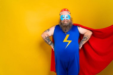 Süper kahraman kostümlü komik şişman adam özel güçleri olan süper insan rolünde, renkli arka planda bir portre.