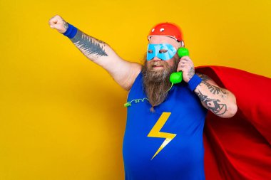 Süper kahraman kostümlü komik şişman adam özel güçleri olan süper insan rolünde, renkli arka planda bir portre.