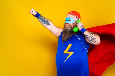 Süper kahraman kostümlü komik şişman adam özel güçleri olan süper insan rolünde, renkli arka planda bir portre.