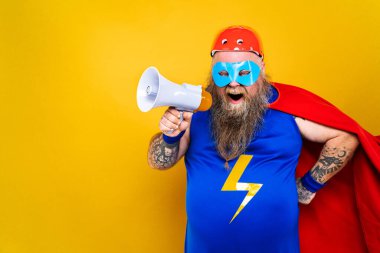 Süper kahraman kostümlü komik şişman adam özel güçleri olan süper insan rolünde, renkli arka planda bir portre.