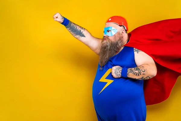 Funny fat man with superhero costume acting as superhuman with special powers, portrait on colored background