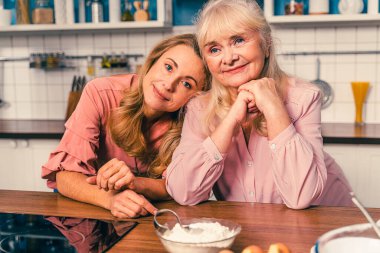 Güzel, son sınıf öğrencisi bir kadın ve kız mutfakta yemek pişiriyor. Büyükanne evde aile ile tatlılar hazırlıyor. Yemek pişirme ve sağlıklı beslenme kavramları.