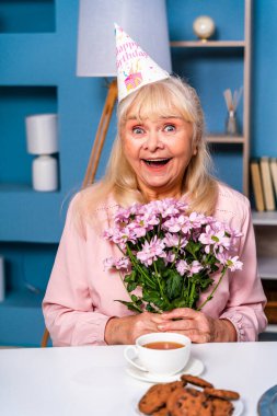 Mutlu bir aile sabah kahvaltısını evde yapar ve doğum gününü kutlar. Büyükannem evde mutfak masasında doğum günü hediyesi olarak çiçek alır.
