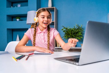 İlkokulda ev ödevi yapan güzel bir kız Coronavirus salgını karantinası sırasında küçük yaşta evde uzaktan öğrenim görüyor.