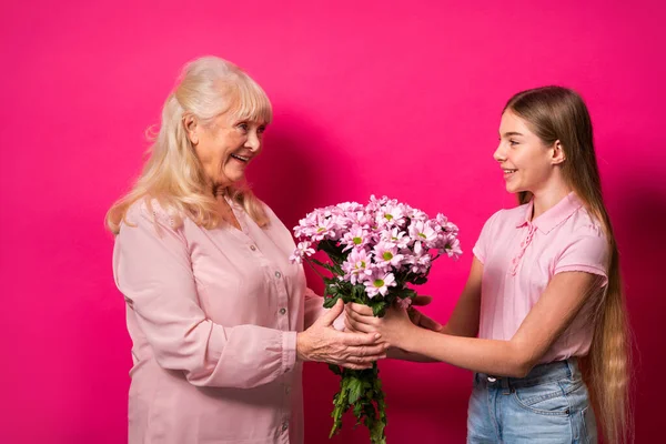 Grandchild presenting flowers to granny at home, happy domestic life moments - Family having fun, concepts about elderly, mult-generation family and relationship