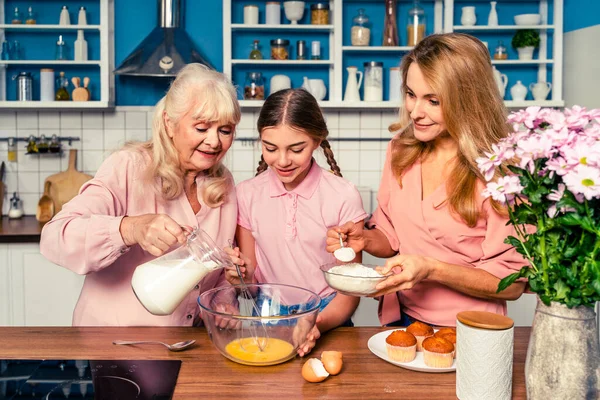 Beautiful senior woman and family baking in the kitchen - Grandmother preparing desserts at home with daughter and nephew, concepts about cooking and healthy eating