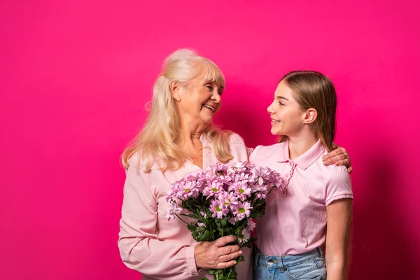 Grandchild presenting flowers to granny at home, happy domestic life moments - Family having fun, concepts about elderly, mult-generation family and relationship