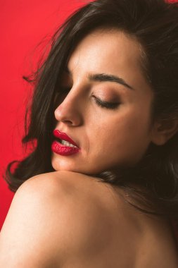 Kırmızı arka planda iç çamaşırlarıyla poz veren güzel bir kadın.