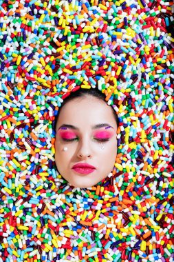 Renkli hapların ve kapsüllerin içine batmış güzel bir kadının sanatsal görüntüsü..