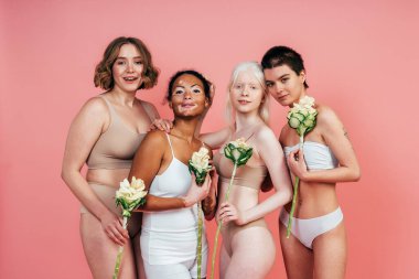 Farklı tür ten rengine sahip çok ırklı bir grup kadın stüdyoda birlikte poz veriyor. Vücut pozitifliği ve kendini kabullenme kavramı