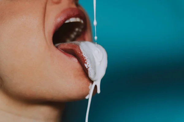 Artistic image of a female mouth with white fluid dripping on her tongue